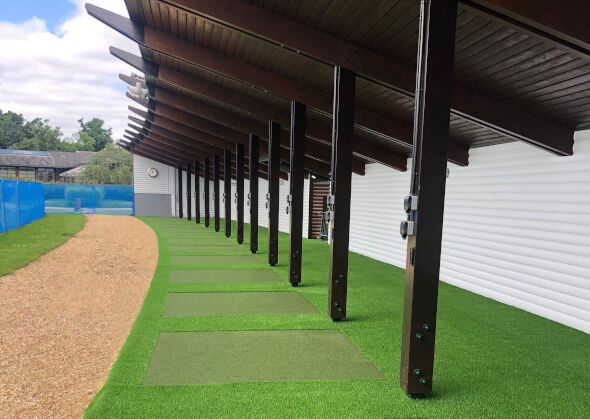 Huntsville Covered outdoor tee line with light green synthetic grass boxes inside a dark green synthetic grass strip